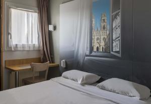 Schlafzimmer mit einem Bett, einem Schreibtisch und einem Fenster in der Unterkunft B&B HOTEL Orléans in La Chapelle-Saint-Mesmin