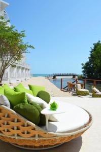 a rattan couch with green pillows and a table at Hotel Gergana - Ultra All Inclusive in Albena
