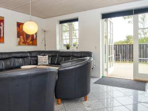 ein Wohnzimmer mit einem Ledersofa und einem Tisch in der Unterkunft 10 person holiday home in Ulfborg in Ulfborg