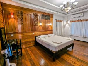 - une chambre dotée d'un lit avec des murs en bois et un lustre dans l'établissement Ziggy Stardust, à Ko Phayam