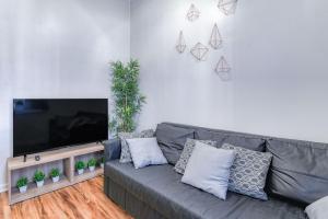 a living room with a gray couch and a flat screen tv at Gorgeous Duplex with parking by JSQ in Jersey City