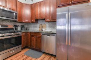 una cocina con armarios de madera y electrodomésticos de acero inoxidable en Gorgeous Duplex with parking by JSQ, en Jersey City