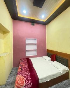 バラナシにあるShivalay paying guest houseのピンクの壁のベッド1台が備わる客室です。