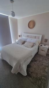 a white bedroom with a large bed and a table at Costa Azul la Herradura in Coquimbo