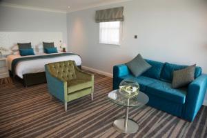 sala de estar con sofá azul y cama en St George's Hotel - Llandudno en Llandudno