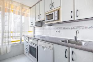 kuchnia z białymi szafkami i zlewem w obiekcie Don Miguel 1 18-A Levante Beach Apartment w mieście Benidorm