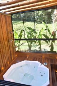 a bath tub in front of a large window at La Nostra Terra in Nova Veneza