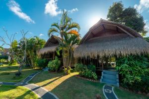 a house with a thatched roof and a yard at brothers bungalows in Jimbaran