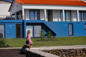 Ein junges Mädchen, das vor einem blauen Haus läuft. in der Unterkunft Villas da Salga in Angra do Heroísmo