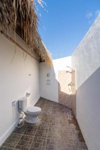 a bathroom with a toilet with a straw roof at brothers bungalows in Jimbaran +25 photos