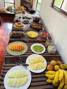 a long table with plates of food and fruit at Pousada do Sol in Alto Paraíso de Goiás