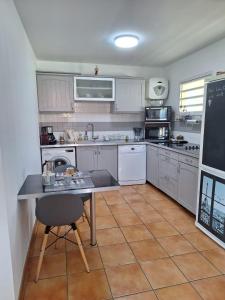 uma cozinha com armários brancos, uma mesa e um quadro negro em BEL APPARTEMENT T2 VUE MER - SAINTE LUCE em Sainte-Luce