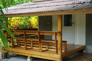 una terraza de madera con techo en una casa en Thong Tiny House en Phatthalung