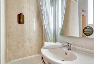 a bathroom with a sink and a mirror and a tub at B&B HOTEL Clermont-Ferrand Le Brézet Aéroport in Clermont-Ferrand +14 photos