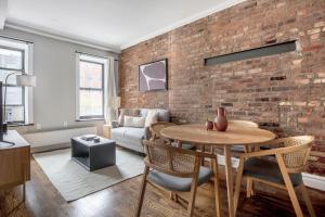 ein Wohnzimmer mit einer Ziegelwand, einem Tisch und Stühlen in der Unterkunft East Village 2br w wd nr union square NYC-1260 in New York