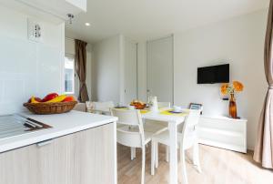 una cucina e una sala da pranzo con tavolo e sedie bianchi di Camping Marelago a Caorle
