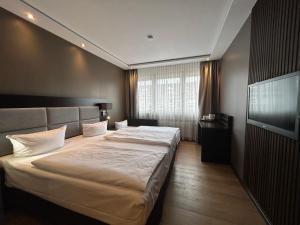 a bedroom with two beds and a flat screen tv at Hotel am Karlstor in Karlsruhe