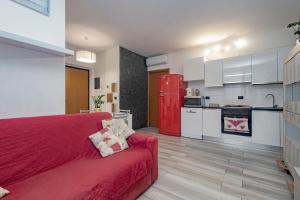 ein Wohnzimmer mit einem roten Sofa und einer Küche in der Unterkunft Bomboniera Milano zona RHO FIERA - Bilocale 70mq in Senago