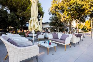 a group of chairs and tables with an umbrella at Hotel Pinija in Petrcane