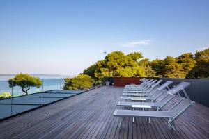 a row of white chairs sitting on top of a deck at Hotel Pinija in Petrcane