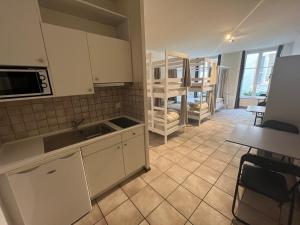 a kitchen with white cabinets and a table and a room at Auberge de jeunesse hyper centre de Neuchâtel in Neuchâtel