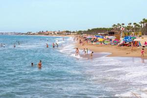 a crowded beach with many people in the water at Arc de Bará Camping & Bungalows in Roda de Bará