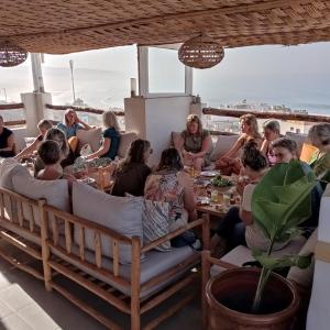 a group of people sitting around a table on a roof at BigBlue Hostel - Taghazout in Taghazout