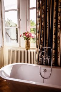 une baignoire avec un vase de fleurs dans la fenêtre dans l'établissement Château de la Grange Moreau, à Vallon-sur-Gée