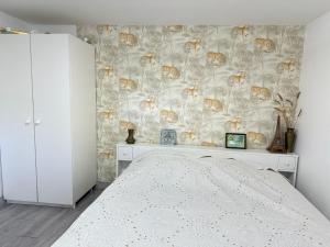 a bedroom with a bed and a wall covered in wallpaper at 10 min to Disneyland Paris, a T3 renewed in a big house, all equiped for 4 or 6 persons in Collégien