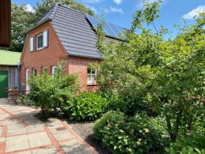 ceglany dom z mnóstwem roślin przed nim w obiekcie Eichenhof (Vollerwiek) w mieście Grothusenkoog