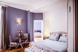 1 dormitorio con paredes de color púrpura, 1 cama y 1 mesa en Château de la Grange Moreau, en Vallon-sur-Gée