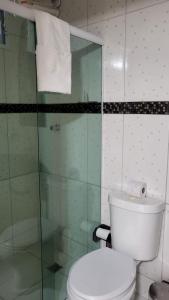 a bathroom with a toilet and a glass shower at Pousada Azul Atlântica in Guarapari