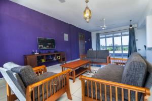 ein Wohnzimmer mit lilafarbenen Wänden sowie einem Tisch und Stühlen in der Unterkunft luzlux penthouse Diani in Ukunda