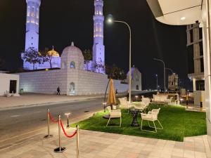 een groep stoelen en tafels voor een gebouw 's nachts bij Hill Top Muscat in Muscat