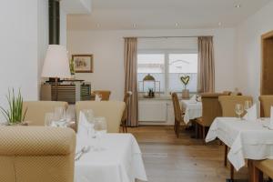 un restaurant avec des tables et des chaises blanches et une fenêtre dans l'établissement B&B Hotel Die Bergquelle, à Flachau