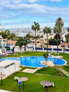 un complejo con una piscina con palmeras y un puerto deportivo en Sueño de Mar, en Denia