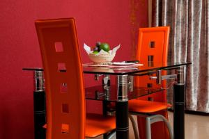 - une table avec des chaises orange et une corbeille de fruits dans l'établissement Gatimene Gardens Hotel, à Meru