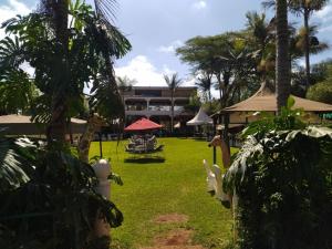 a yard with grass and palm trees and a building at Gatimene Gardens Hotel in Meru