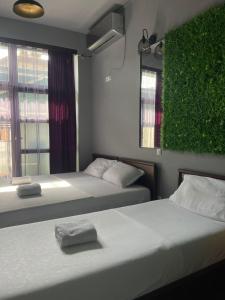 two beds in a room with a green wall at Hotel In Time in Prizren