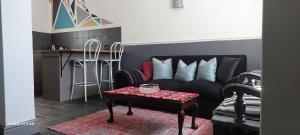 uma sala de estar com um sofá preto e uma mesa em Happy Home - Woodstock em Cidade do Cabo
