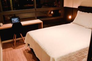 - une chambre avec un lit et un bureau avec un ordinateur portable dans l'établissement Studio 308 no Parque Una com garagem, à Pelotas