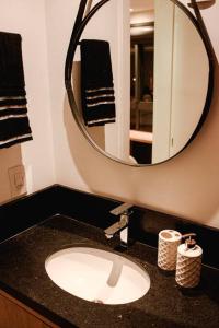 La salle de bains est pourvue d'un lavabo et d'un miroir. dans l'établissement Studio 308 no Parque Una com garagem, à Pelotas