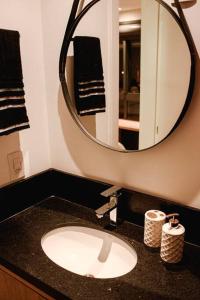 a bathroom with a sink and a mirror at Studio 308 no Parque Una com garagem in Pelotas +14 photos