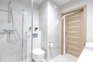 uma casa de banho branca com um WC e um chuveiro em Apartament 8B Wały Chrobrego Szczecin em Szczecin