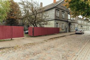 een lege straat met een rood hek en een huis bij Barinu apartments in Liepāja
