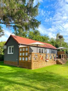 uma pequena casa com um deque e um quintal em Jak Tu Ładnie - Osada i Siedlisko em Mikolajki