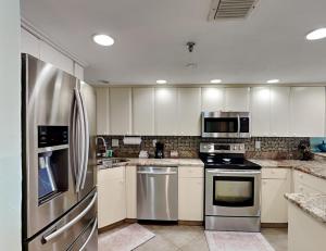 a kitchen with white cabinets and stainless steel appliances at Oceanside Retreat 804 in Ormond Beach