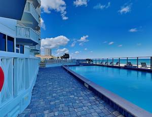 a swimming pool next to a building and the ocean at Oceanside Retreat 804 in Ormond Beach