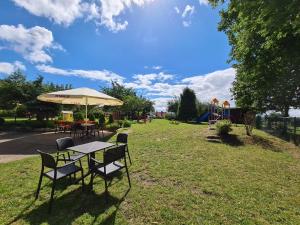 una mesa y sillas con una sombrilla y un parque infantil en Ostrzycka Gościna u Maryli, en Ostrzyce