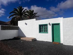 a white building with a green door and a palm tree at Apartamento en el centro de Lanzarote in Tiagua